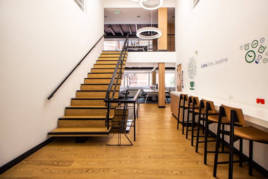 Bright contemporary office interior featuring wooden stairs and high chairs. Ideal for workspace inspiration.
